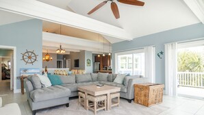 A spacious living area with a large sectional sofa, a wooden coffee table, and a ceiling fan.