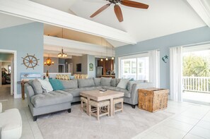 A spacious living area with a large sectional sofa, a wooden coffee table, and a ceiling fan.