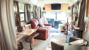 A cozy RV interior with a sofa, a dining table, and a TV mounted on the wall.