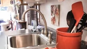 A kitchen with a stainless steel sink, a red spice rack, and a patterned cloth on the counter.
