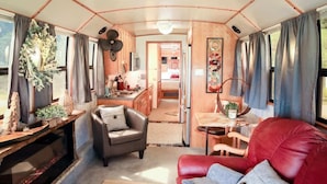 A cozy interior with a living area, kitchen, and dining space, featuring a red sofa, a small table, and a kitchen counter.