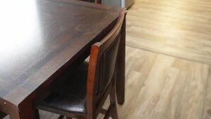 Een eetruimte met een houten tafel en stoelen, een keuken met licht houten vloeren, en een koelkast.