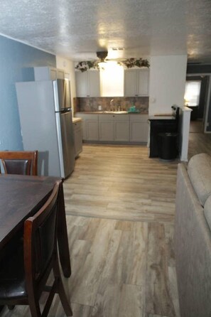 A kitchen with a dining table and chairs, a refrigerator, cabinets, and a sink.