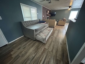 A compact living space with a sofa, a small couch, and a television mounted on the wall.