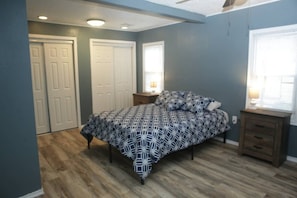 A bedroom with a bed, two nightstands, a window, and a door.