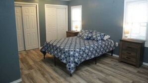 Een slaapkamer met een bed, twee nachtkastjes en een raam.