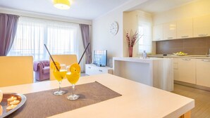A modern hotel room with a dining area, a kitchen, and a living space.