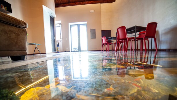 Une pièce spacieuse avec une grande table en verre, des chaises rouges et un canapé.