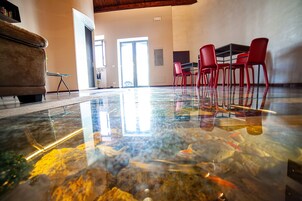 Una habitación amplia con una gran mesa de vidrio, sillas rojas y un sofá.