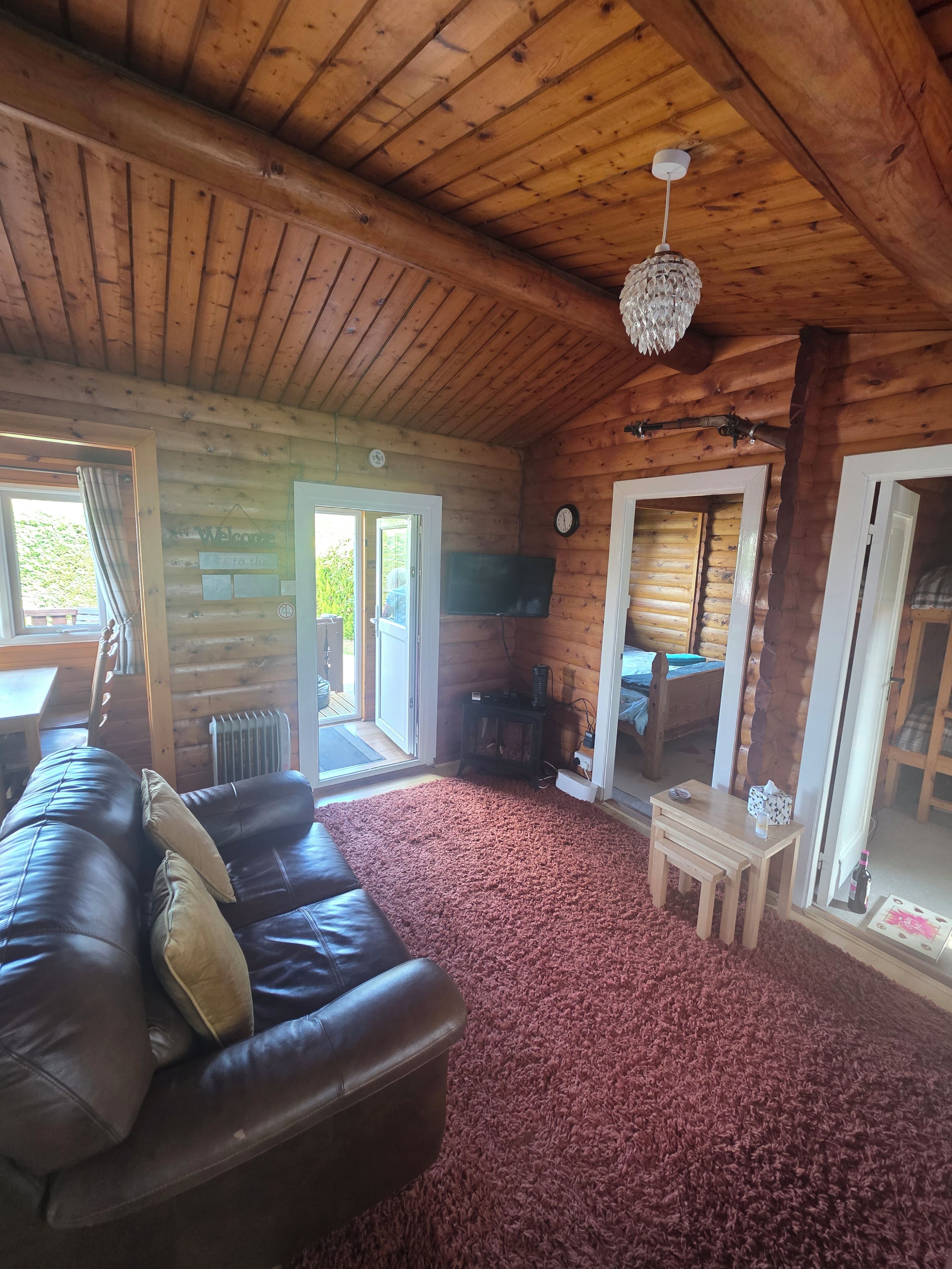 L’intérieur d’une cabane en rondins, avec un canapé en cuir, une petite table et un sol recouvert d’une moquette.