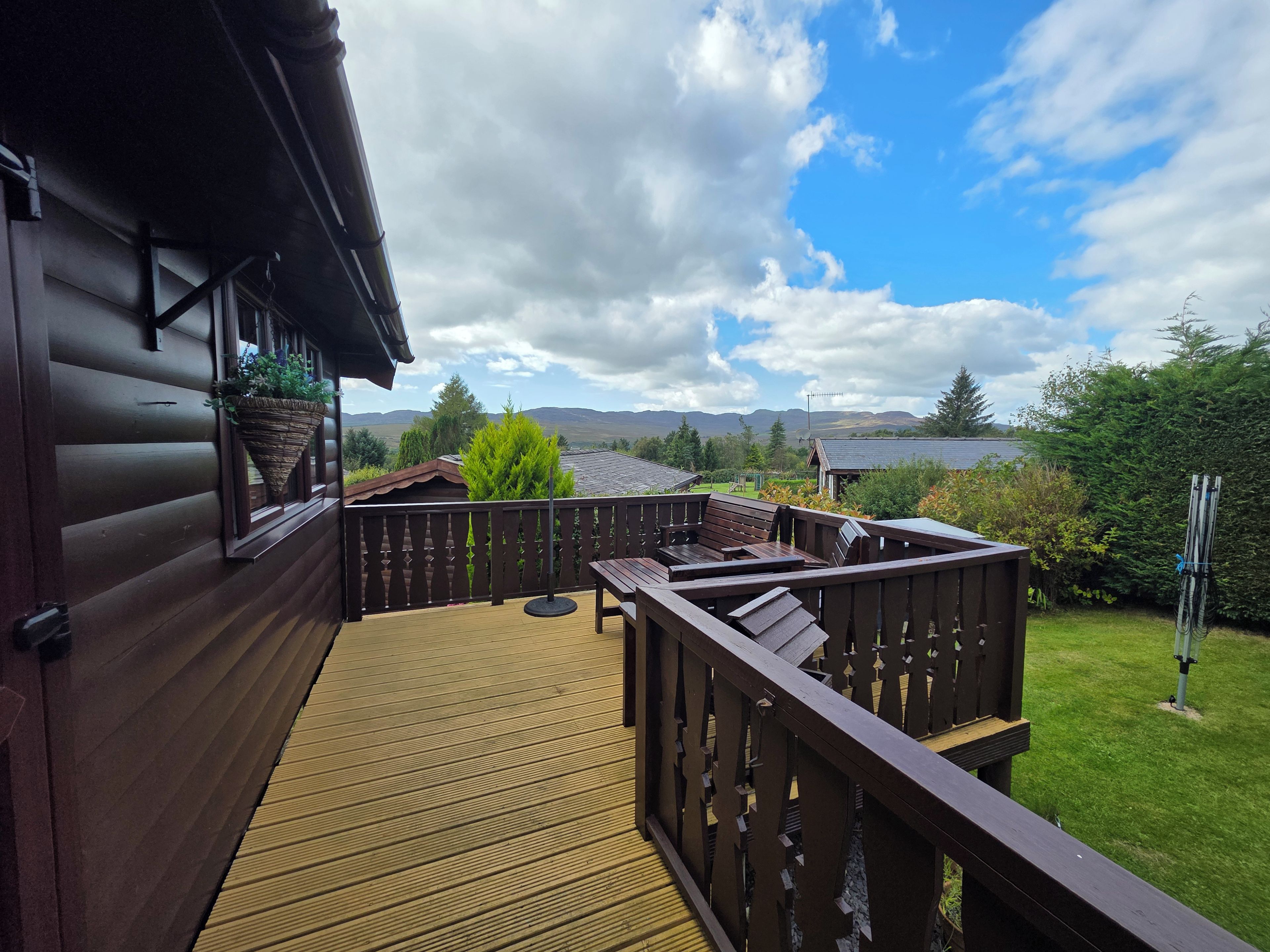 Um deck de madeira com vista para um lago e montanhas.