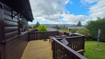 Um deck de madeira com vista para um lago e montanhas.