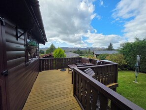 Una terraza de madera con vista a un lago y montañas.