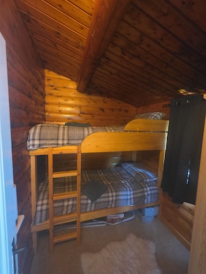 Ein Etagenbett mit einer Leiter, Holzwänden und einem Vorhang.