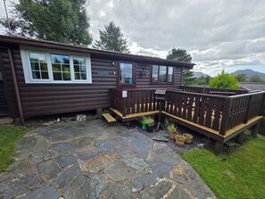 Eine Hütte mit gepflastertem Eingang, einer Holzdielen-Terrasse und einem Schild mit der Aufschrift 'Rhino View Cabin 1st'.