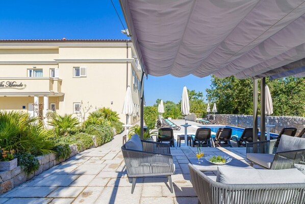 Un espace extérieur avec une piscine, des chaises longues et des parasols, entouré de verdure et bordé d’un bâtiment sur lequel est apposée une enseigne indiquant « La Monte ».