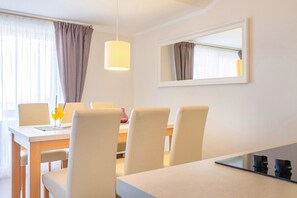 A dining area with a table, chairs, and a hanging light fixture.