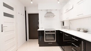 A modern kitchen with a built-in oven, white countertops, and black cabinetry. - Warsaw Concierge Square Grzybowski (Warsaw)