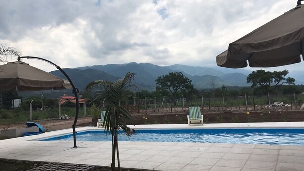 A swimming pool with a view of mountains, surrounded by lounge chairs and umbrellas.