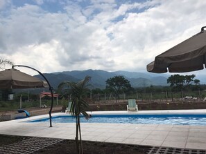Ein Pool mit Bergblick, umgeben von Liegestühlen und Sonnenschirmen.