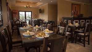 A dining area with multiple tables set for a meal, featuring dark wooden chairs and glass tables.