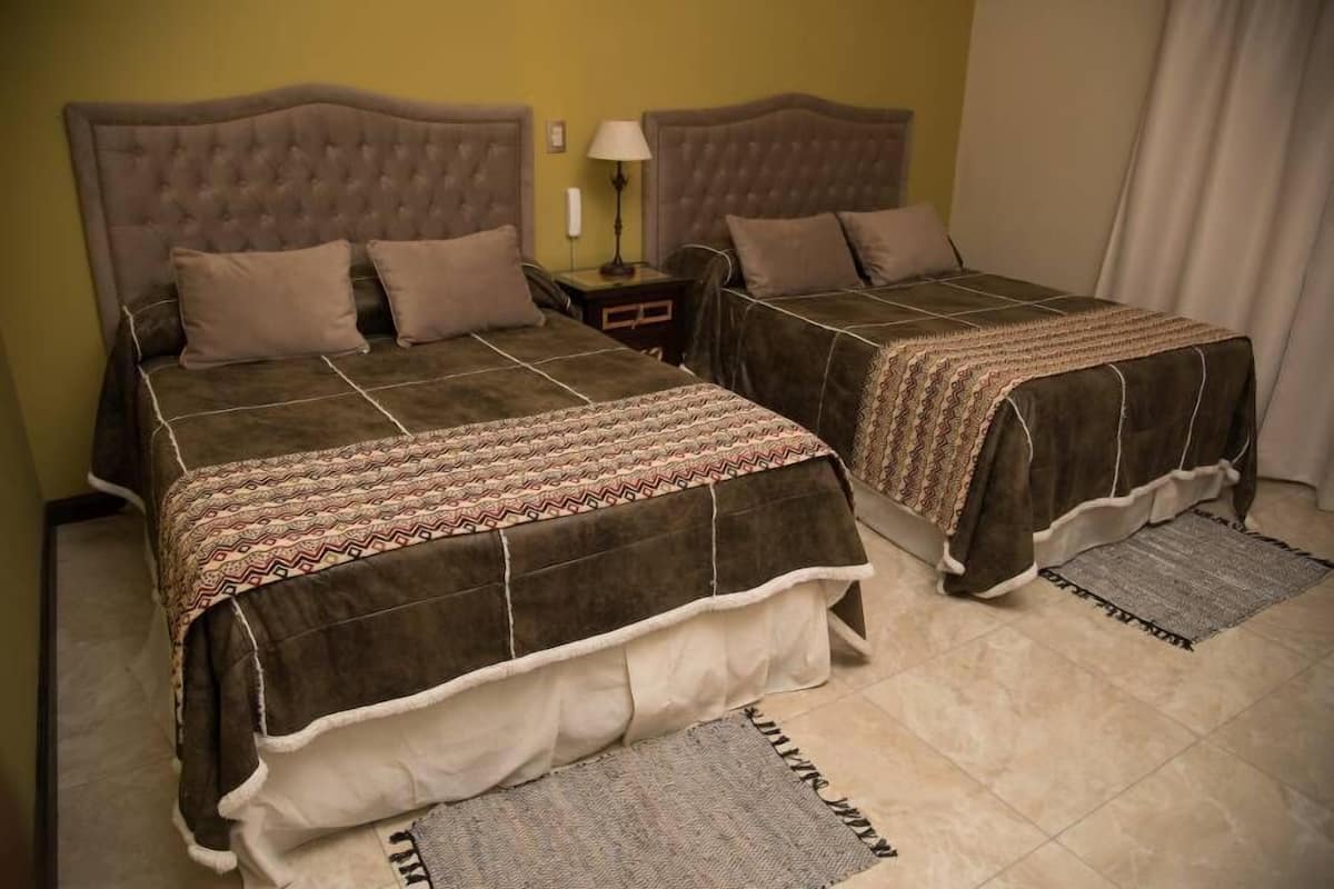 Una cama doble con cabecera marrón y colcha estampada.