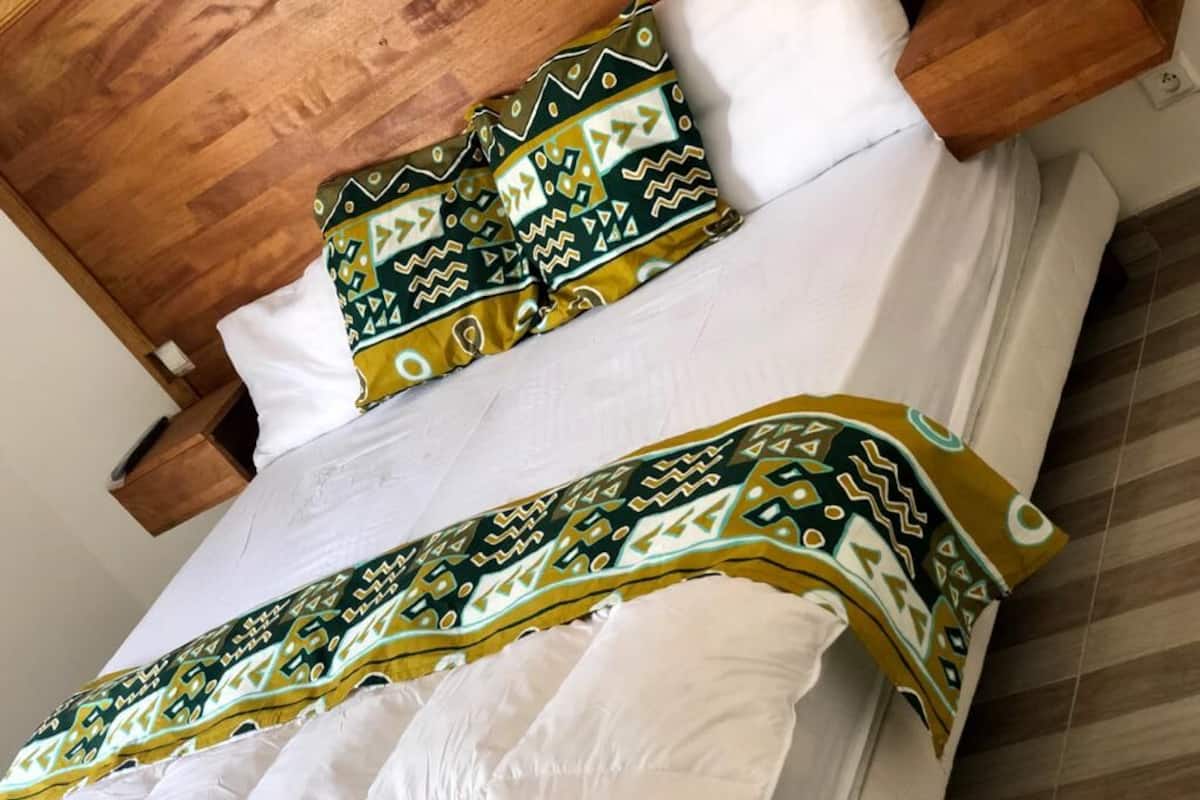 A bed with white linens and a patterned blanket.