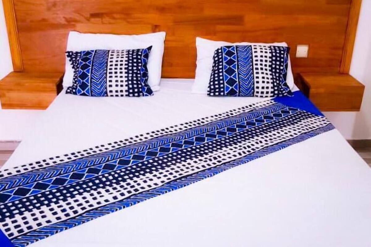 A bed with a patterned bedspread and two pillows with a geometric design.