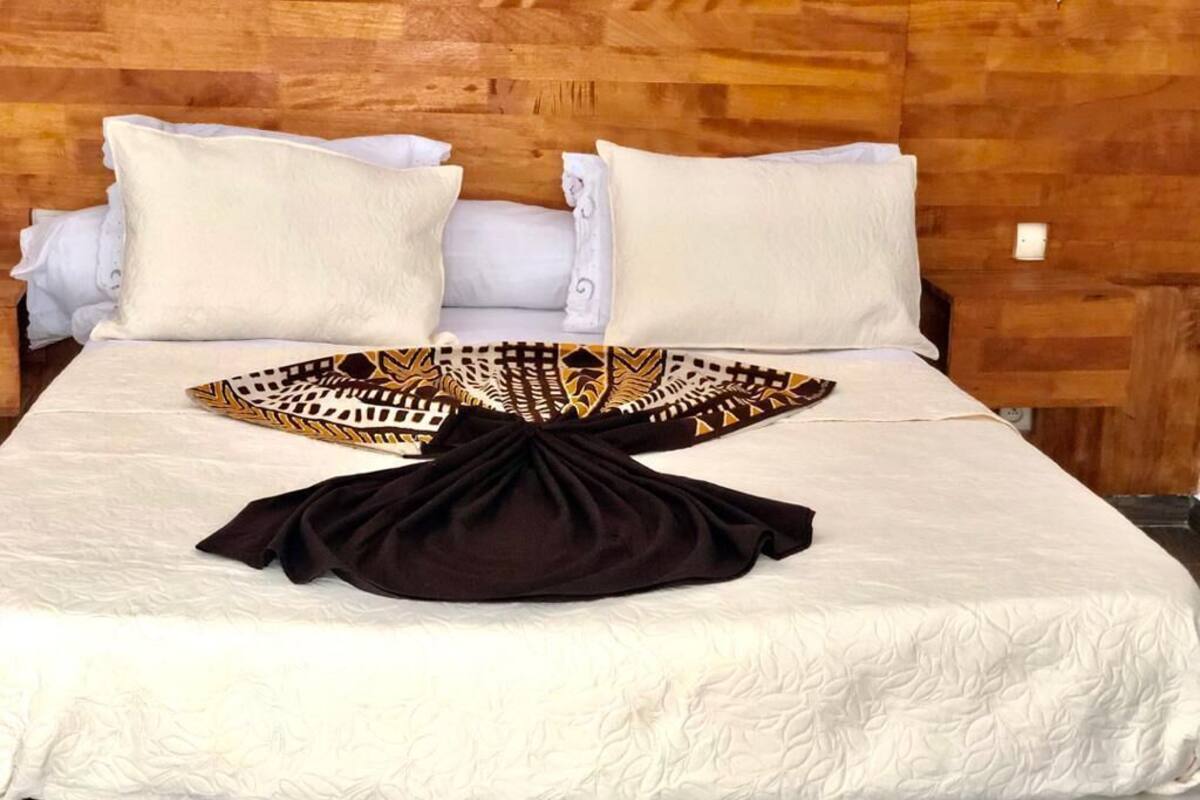A neatly made bed with a patterned throw and a black garment on the bed.