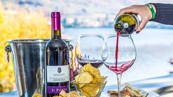 Una botella de vino, dos copas, un cubo y aperitivos sobre una mesa con una vista panorámica al fondo.