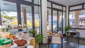 A breakfast buffet with various food items and a view of the mountains through large windows.
