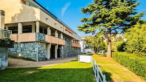 A modern building with a stone facade, a covered walkway, and a well-maintained lawn.