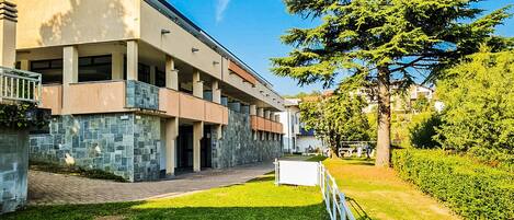 A modern building with a stone facade, a covered walkway, and a well-maintained lawn.