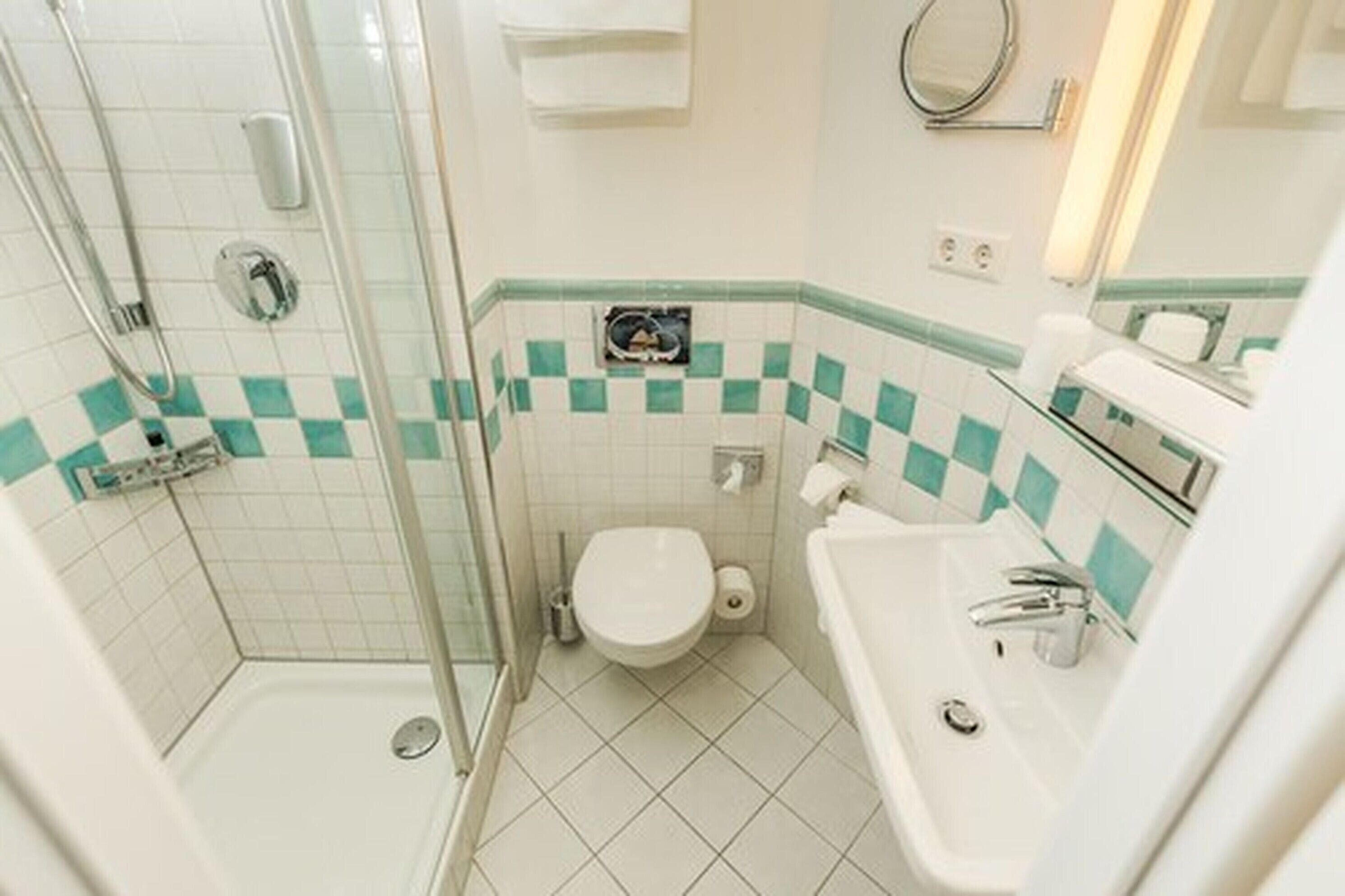 A bathroom with a glass shower enclosure, a toilet, and a sink.