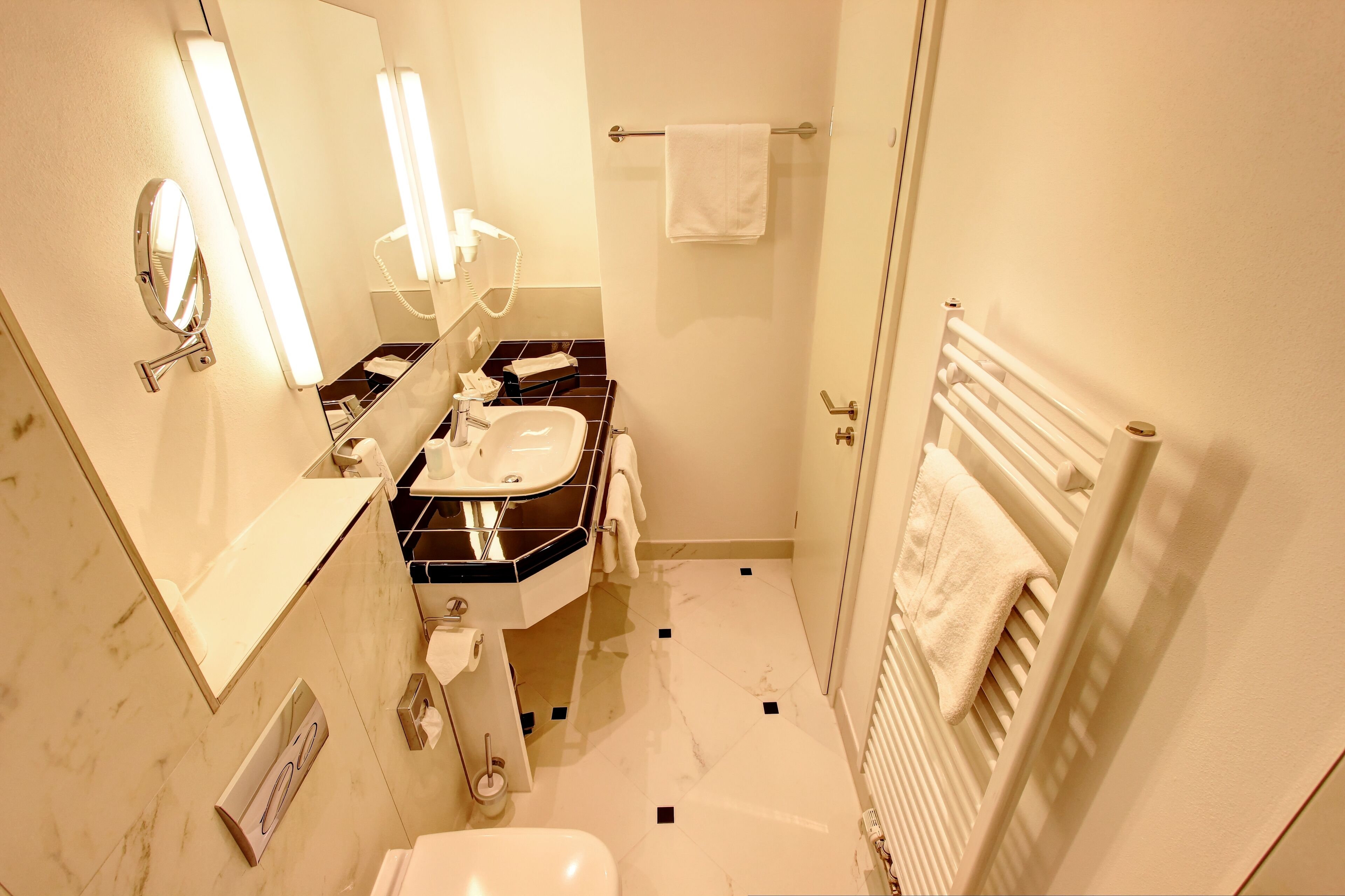 A bathroom with a sink, mirror, towel rack, and a toilet.
