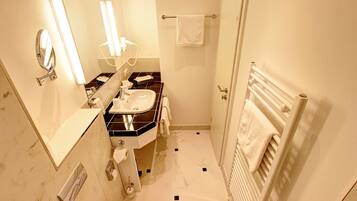 A bathroom with a sink, mirror, towel rack, and a toilet.