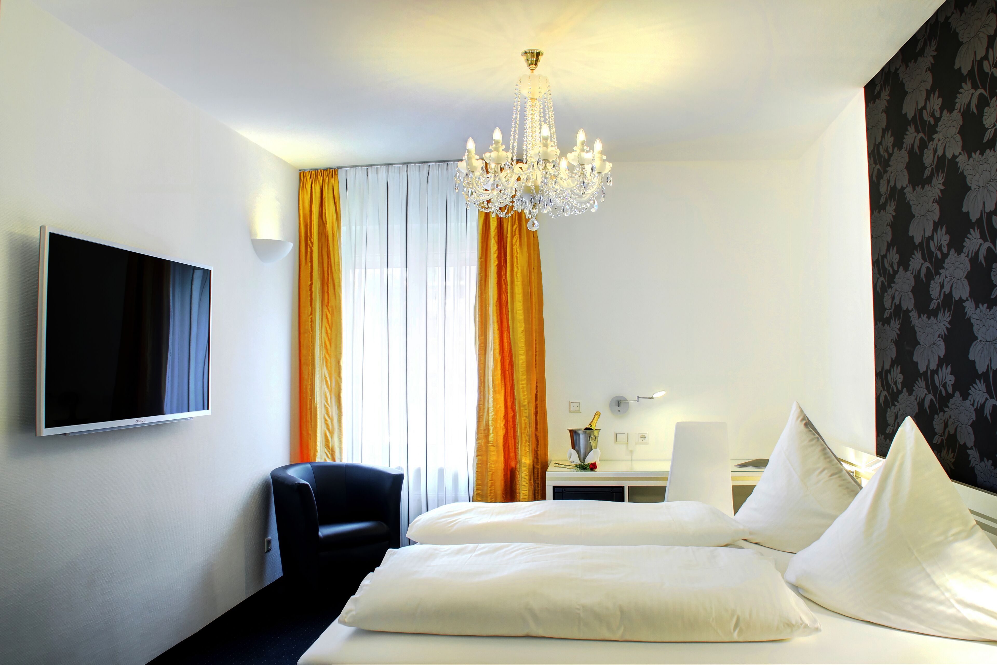 Una habitación de hotel con cama, televisión, escritorio y candelabro.