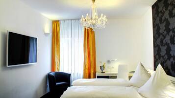 Una habitación de hotel con cama, televisión, escritorio y candelabro.