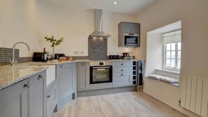 Una cocina moderna con armarios grises, horno integrado, microondas y ventana con vistas.
