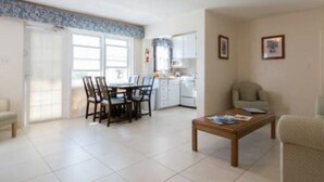 A spacious living area with a dining table and chairs, a kitchen in the background, and a sofa. - Clairfont, Jobson's Cove / Warwick Long Bay/ Horseshoe Beach -  APARTMENT 3 (Warwick)