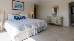 A bedroom with a bed, a dresser, a mirror, and a painting on the wall. - Clairfont, Jobson's Cove / Warwick Long Bay/ Horseshoe Beach -  APARTMENT 6 (Warwick)