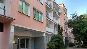 A multi-story residential building with balconies, a gated entrance, and a paved courtyard.