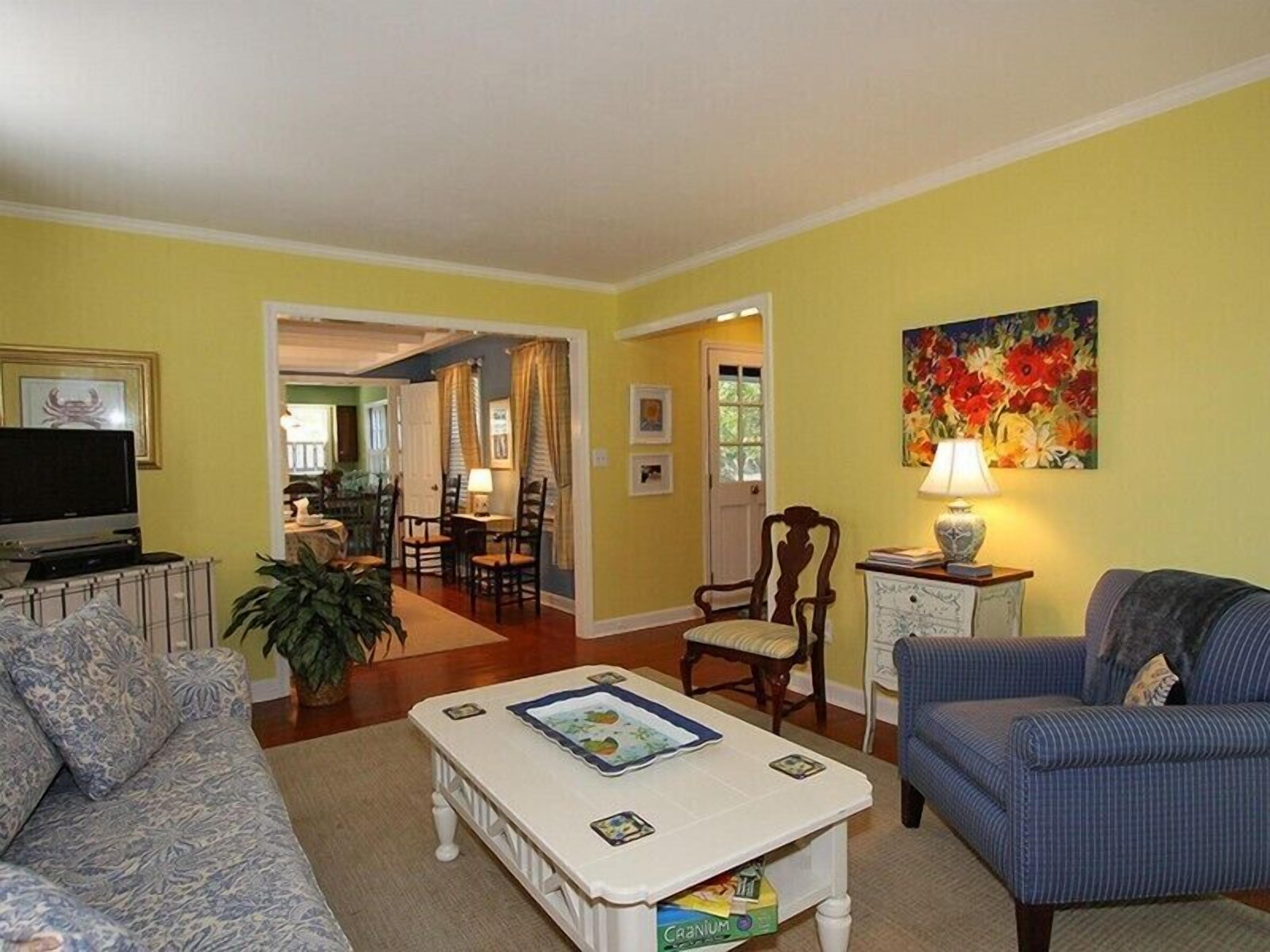 A living room with a sofa, a coffee table, a television, and a painting on the wall.