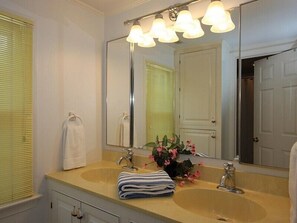 Een badkamer met twee wastafels, een grote spiegel en een raam met luxaflex.