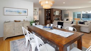Un comedor moderno con una mesa de madera, sillas blancas y una lámpara de araña.