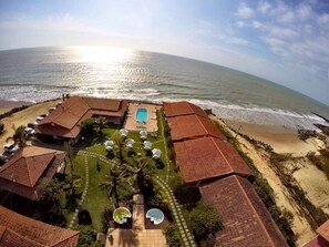 Un complexe hôtelier doté d’une piscine, d’un accès à la plage et de plusieurs villas aux toits recouverts de tuiles rouges.