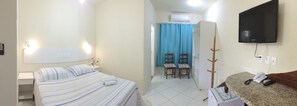 Une chambre d’hôtel avec deux lits, une télévision, un bureau et une salle de bain équipée d’une douche et de chaises.