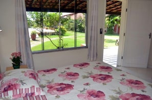 Ein Schlafzimmer mit einem Bett, einem Fenster und Blick auf einen Garten.