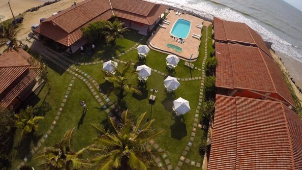 A resort with a swimming pool, lounge chairs, and a beach view.