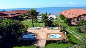 A resort with multiple hot tubs, a pool, and a view of the ocean.